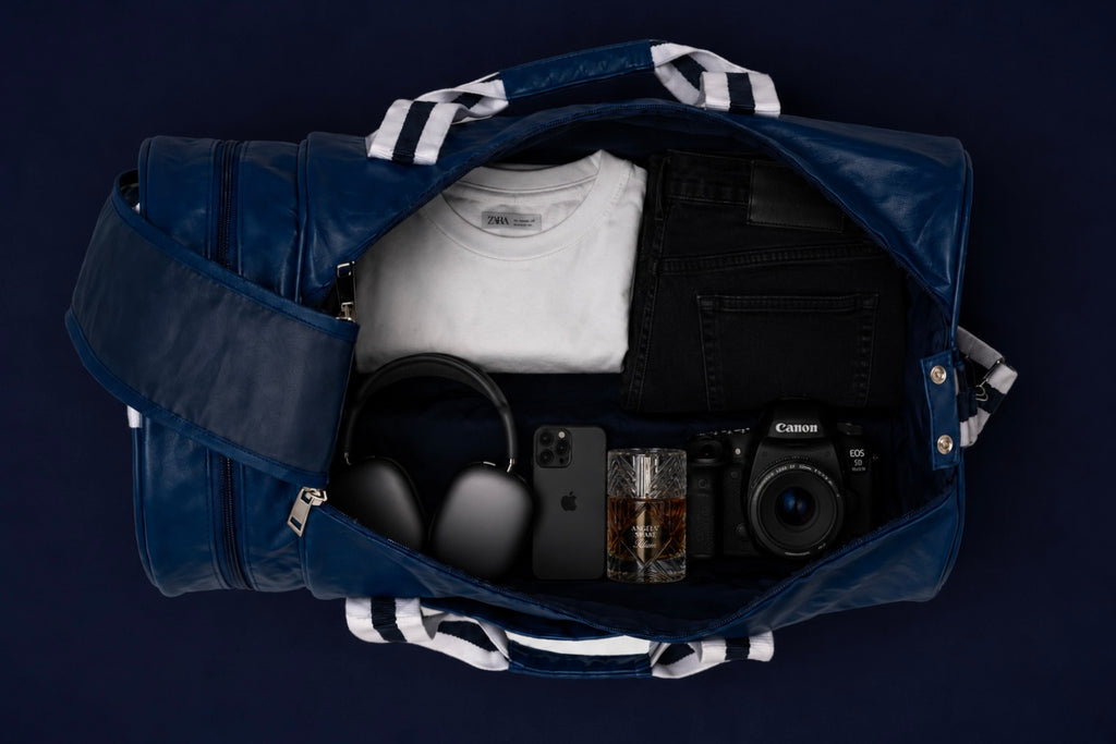 Open a blue Neptune duffle bag packed with clothes, headphones, phone, camera, and travel essentials